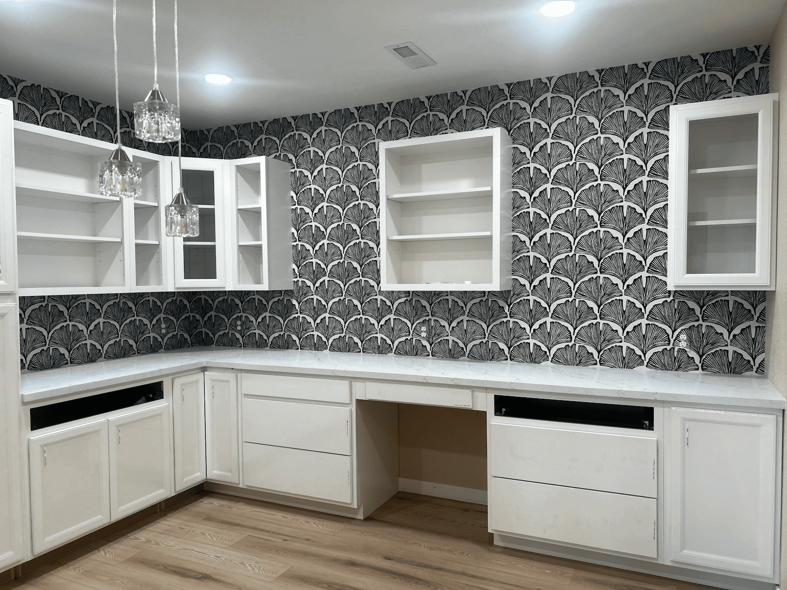 White cabinets with patterned wallpaper in kitchen.