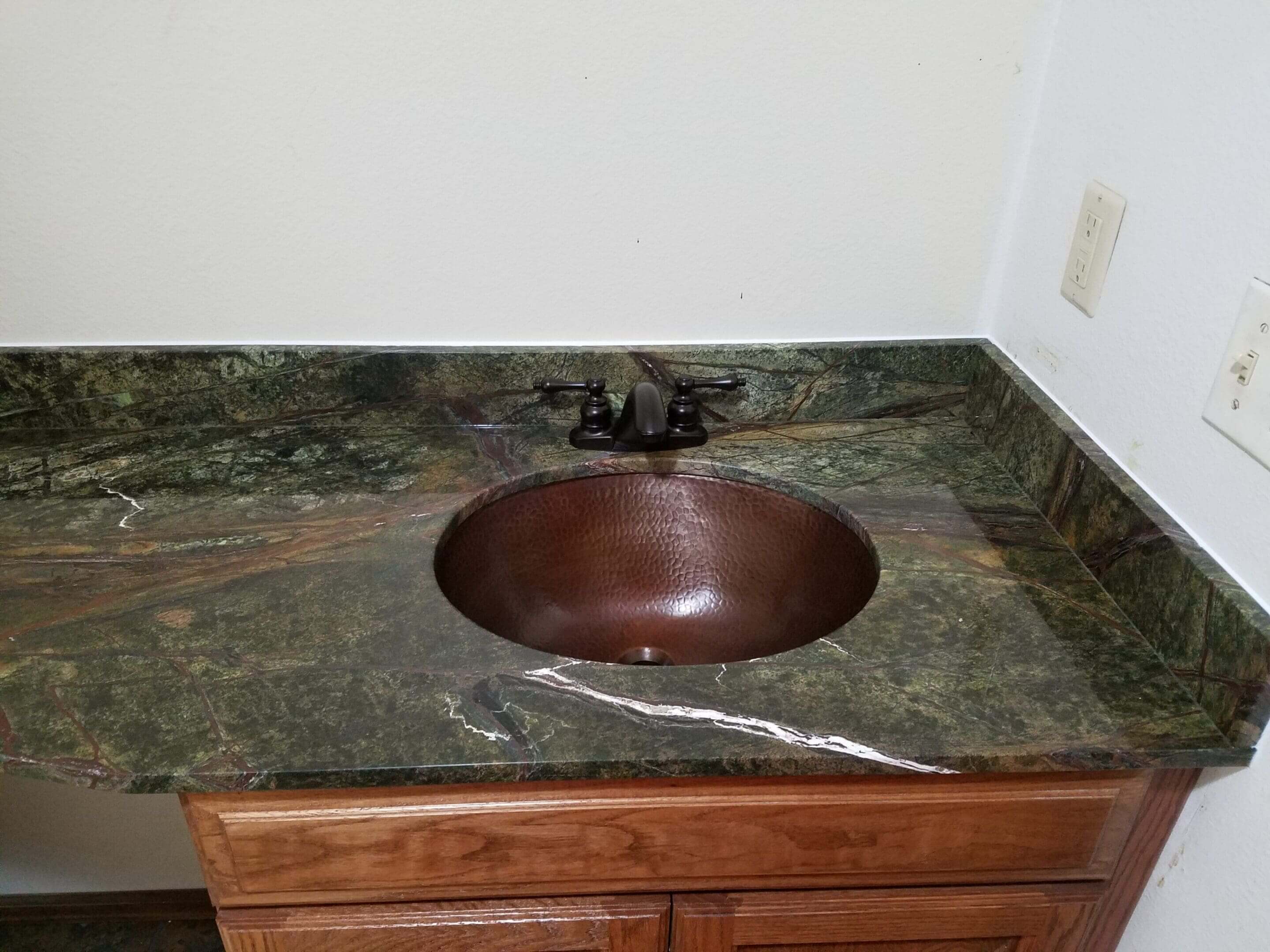 Green marble bathroom sink with faucet.