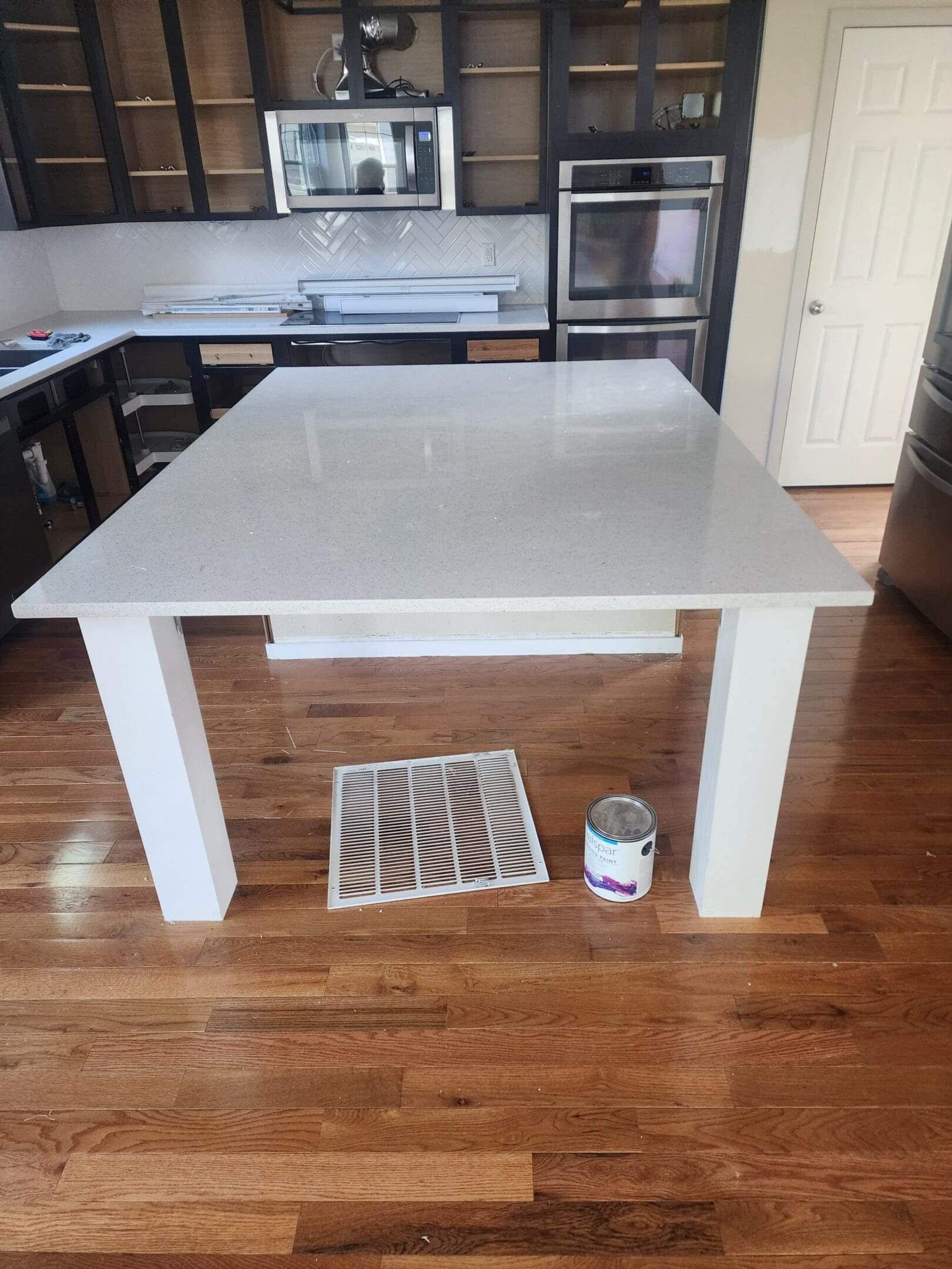Kitchen island with white countertop and hardwood floor.