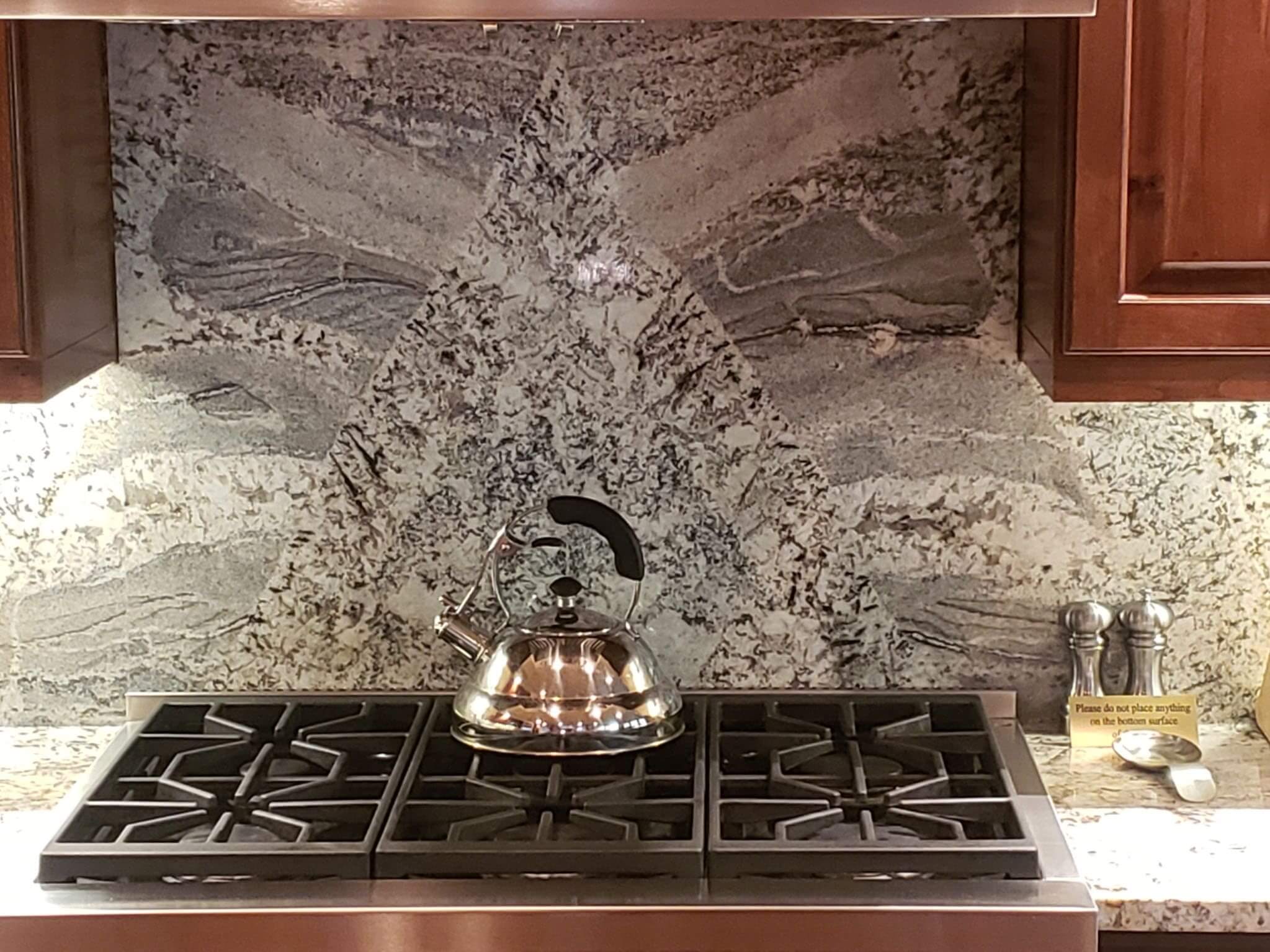 Stove with kettle and marble backsplash.