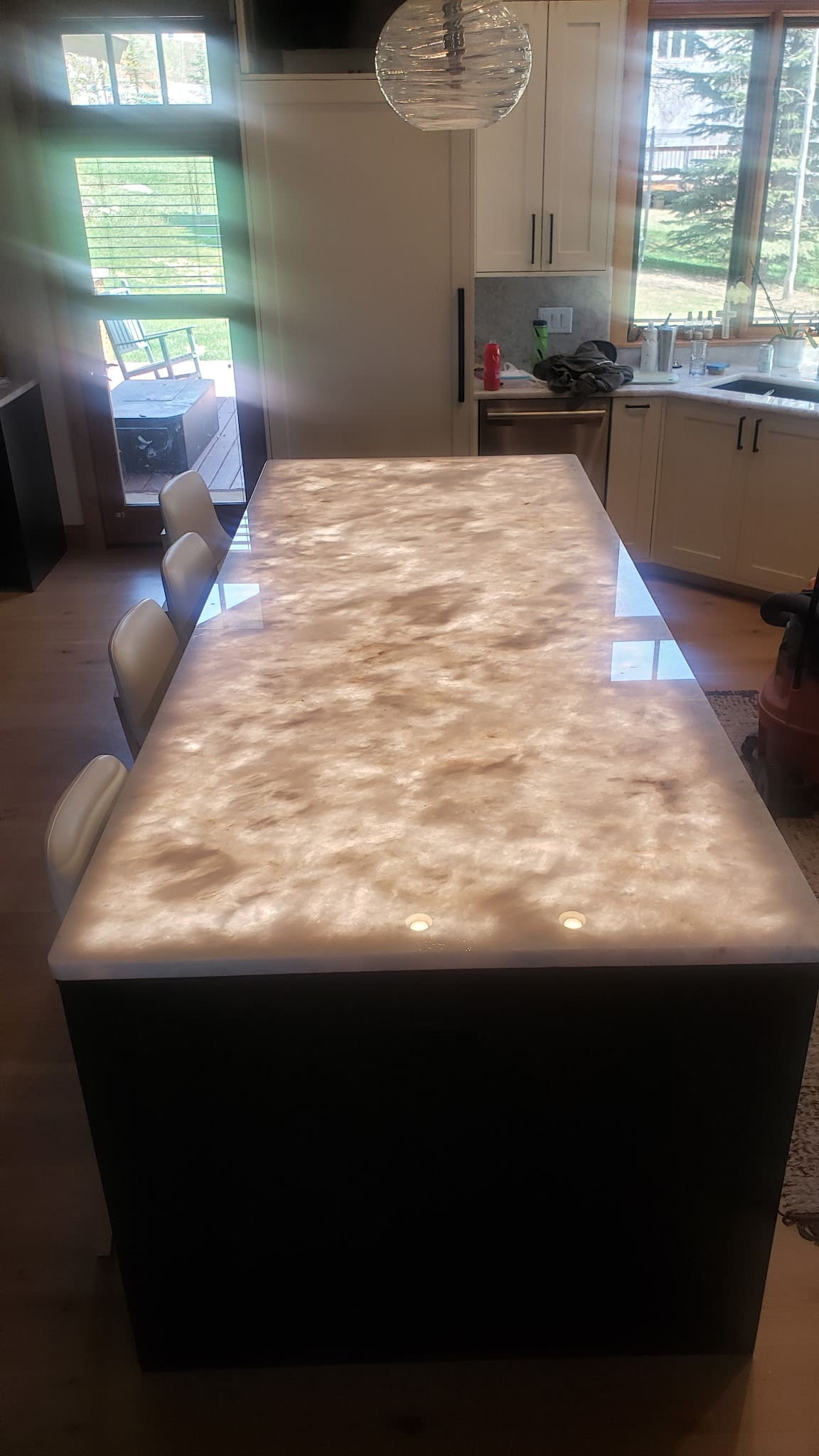 Illuminated kitchen island countertop with bar stools.