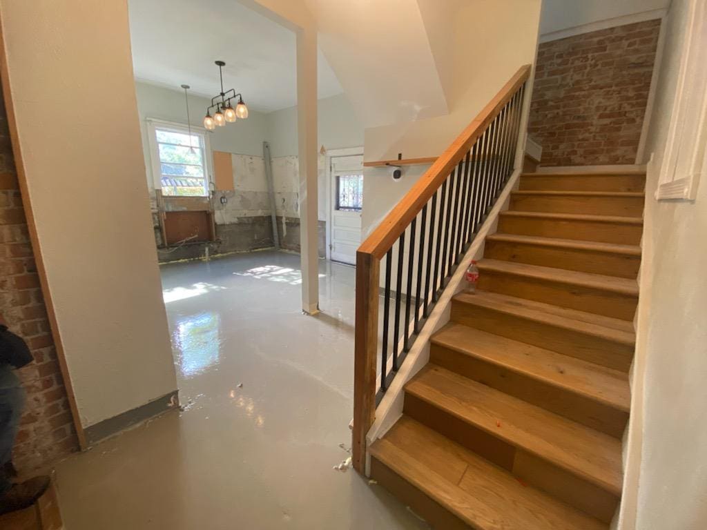 Staircase beside unfurnished room with chandelier.