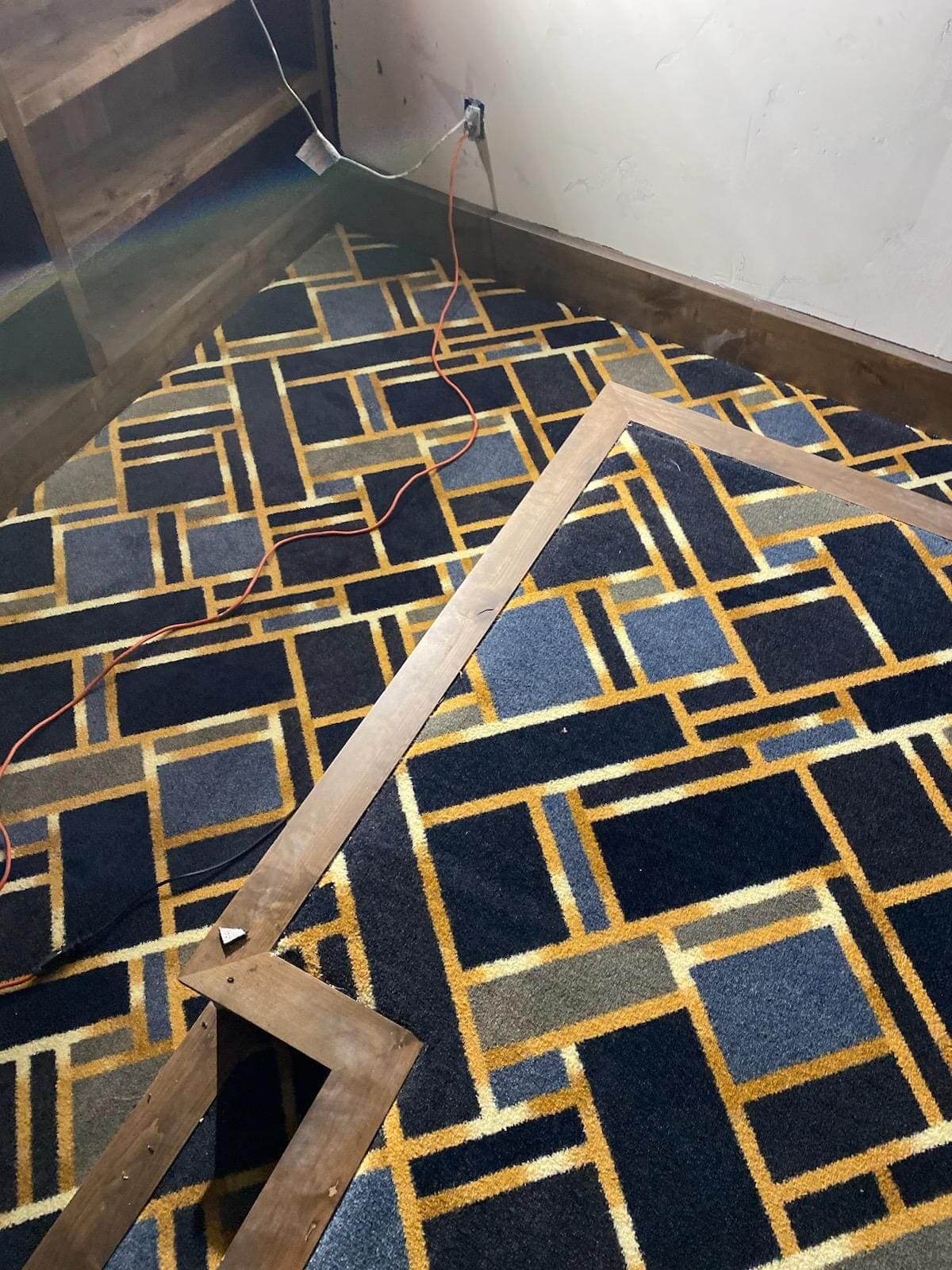 Geometric patterned carpet with wooden frame.