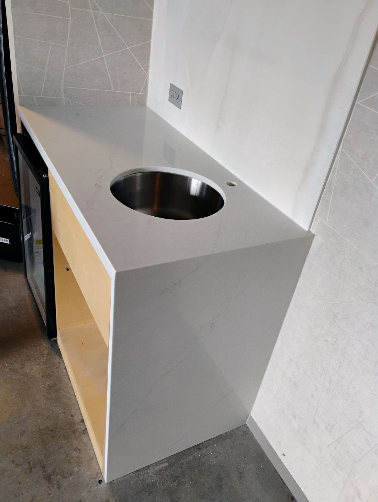 White countertop with round stainless steel sink.