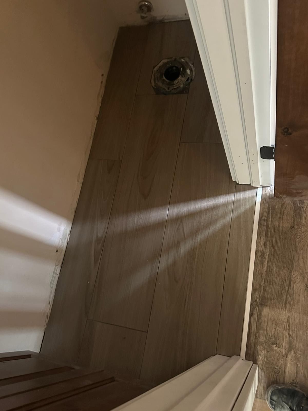 Empty bathroom with wooden floor and door ajar.