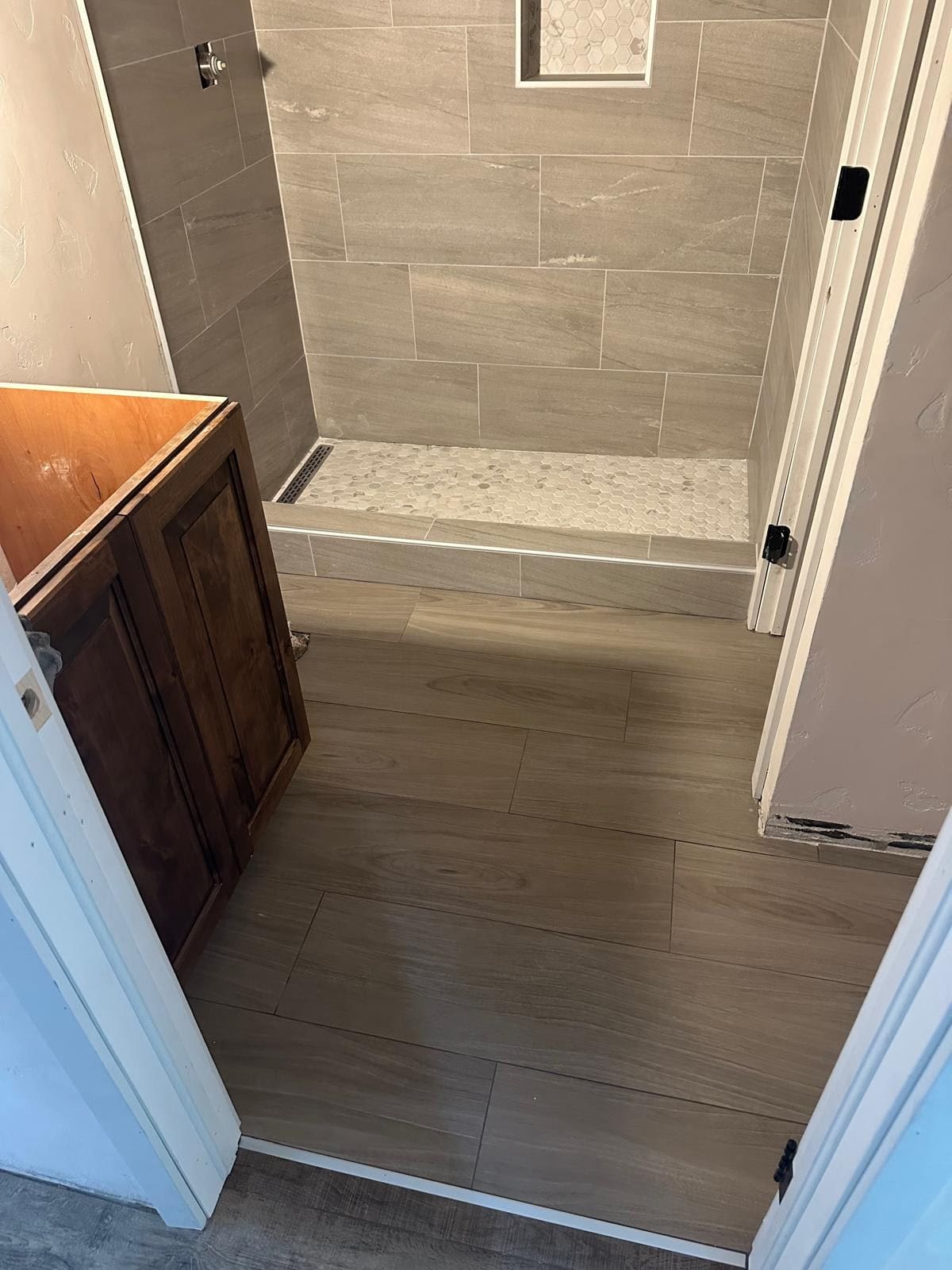 Bathroom with tiled shower and wooden cabinet.
