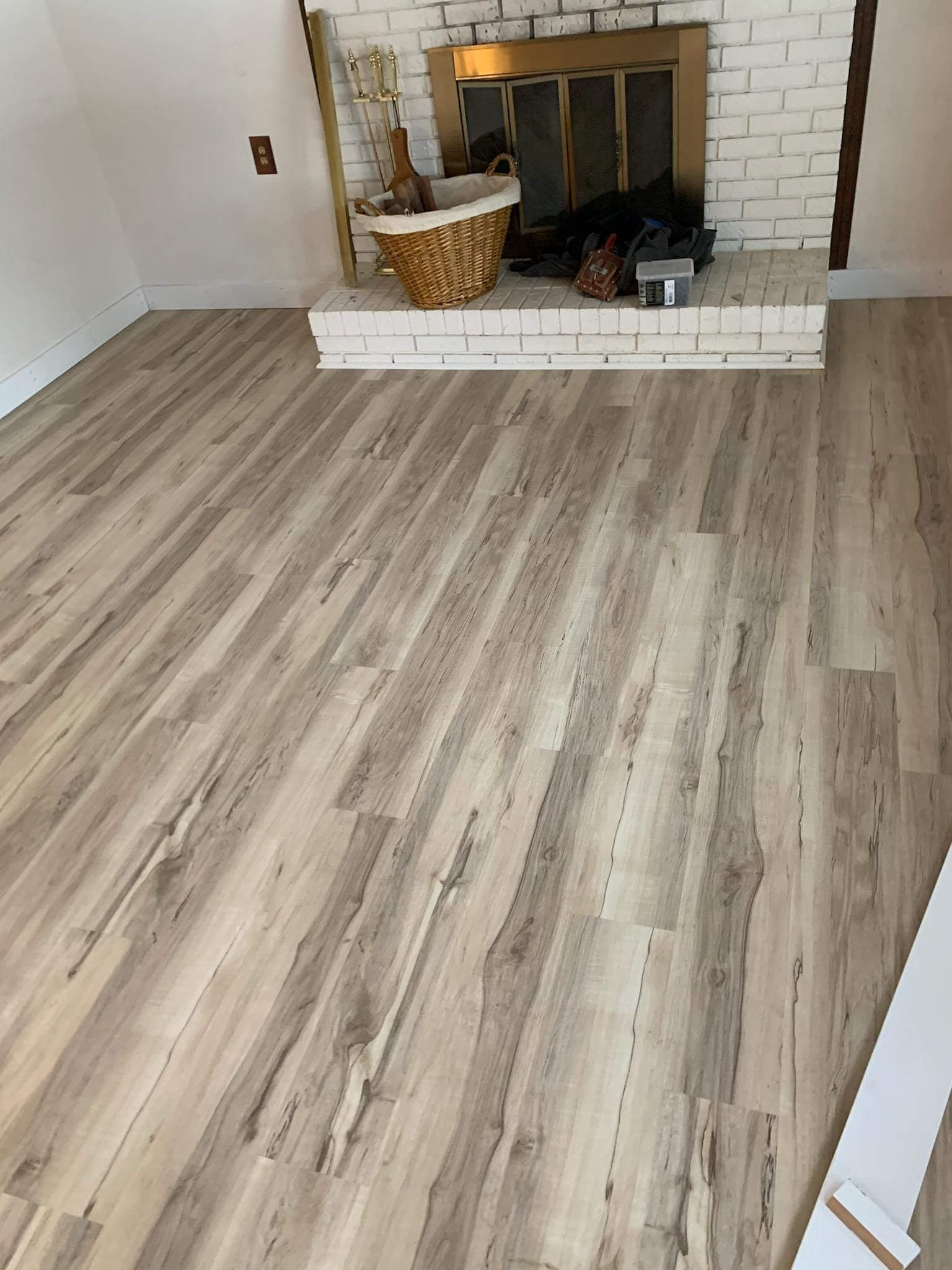 Wooden floor in room with fireplace.