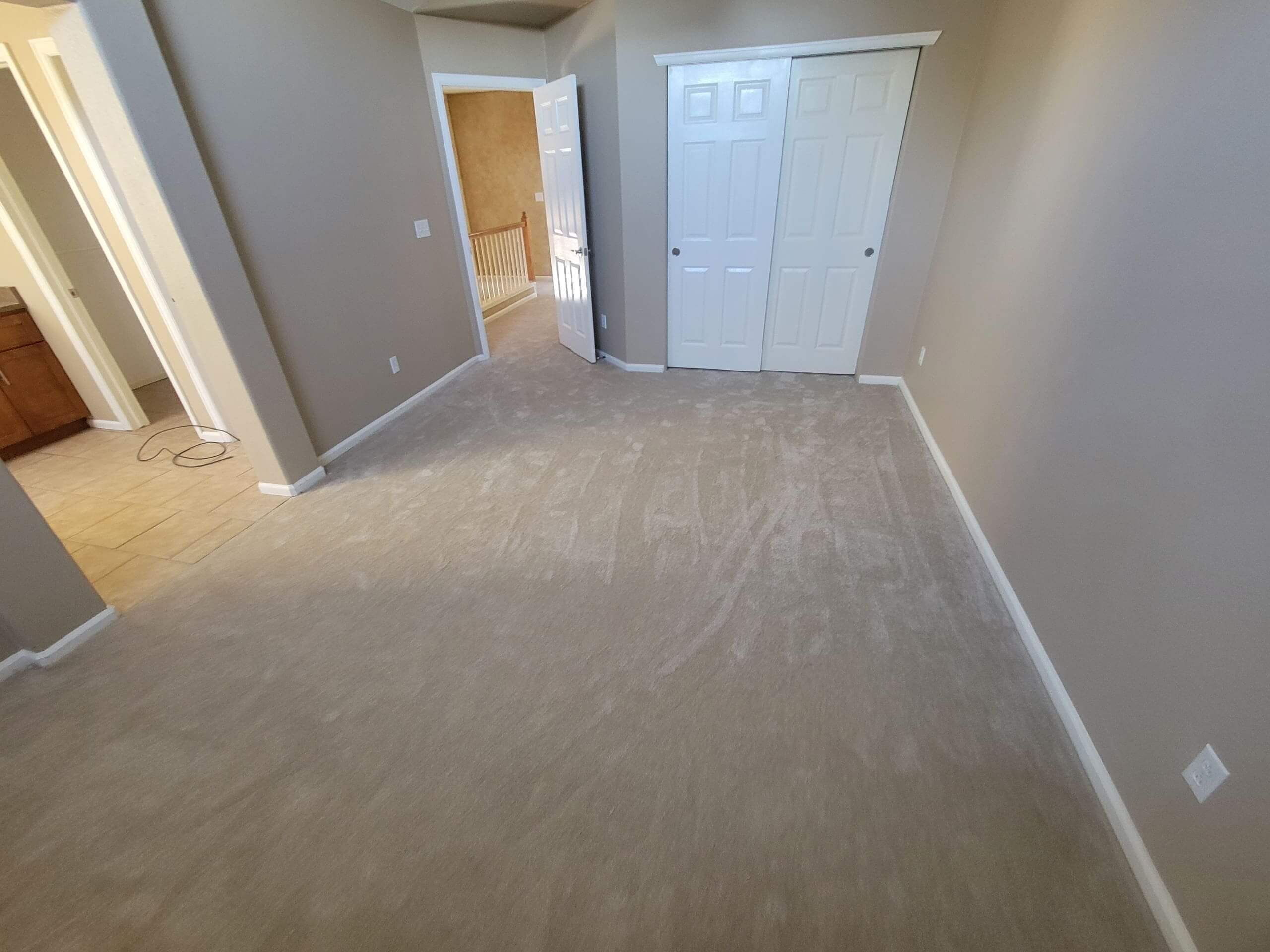 Empty carpeted room with closed closet doors.
