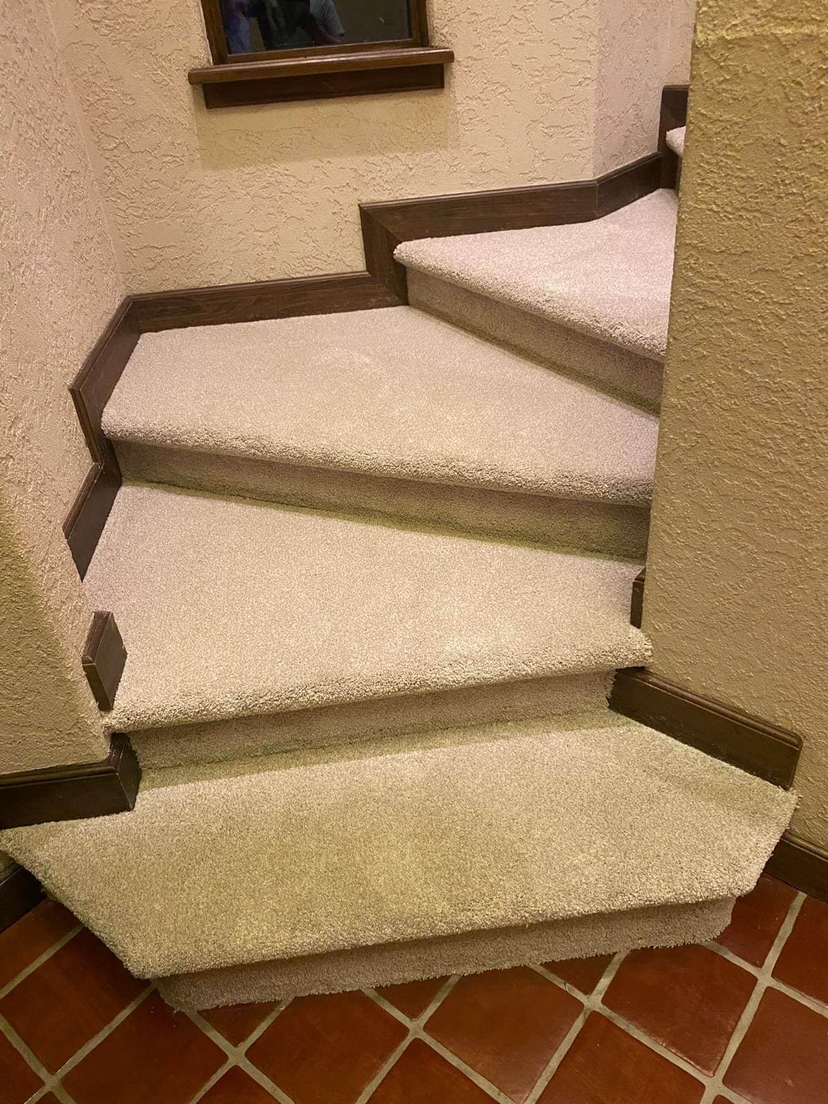 Carpeted staircase with brown trim.