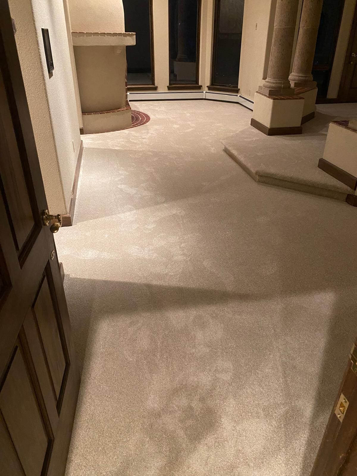 Spacious room with beige carpet and columns.