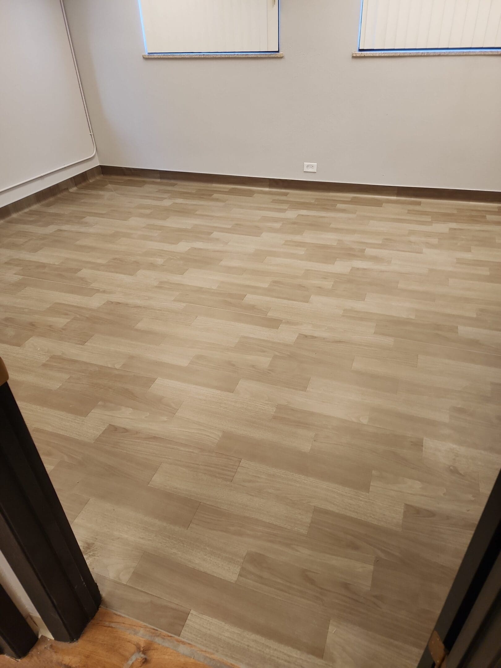 Empty room with light wood laminate flooring.