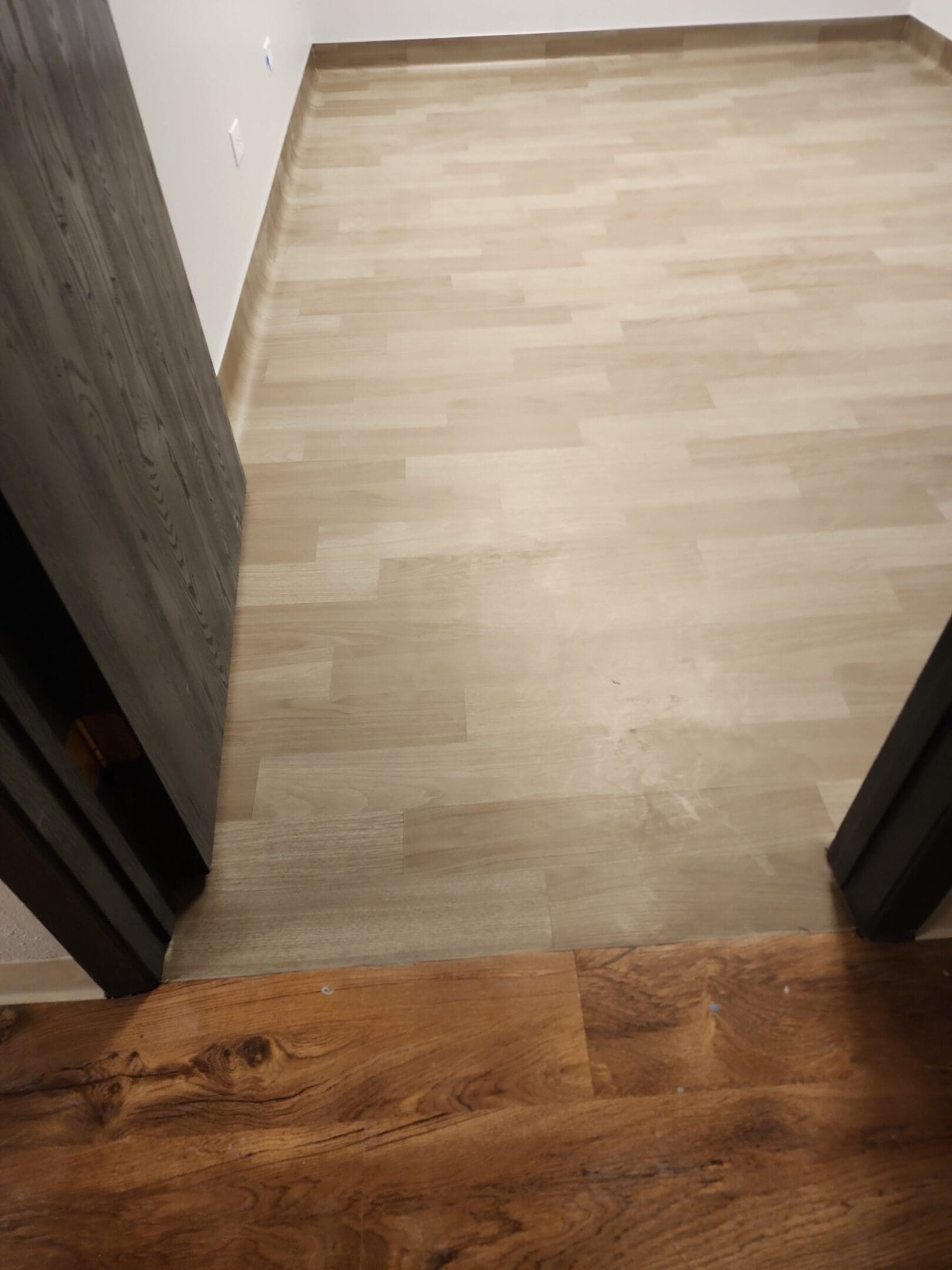 Wooden flooring transition between two rooms.