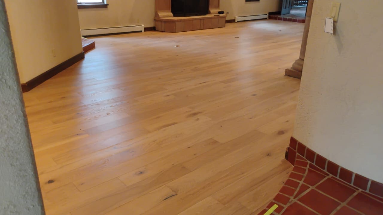 Spacious room with wooden flooring and fireplace.