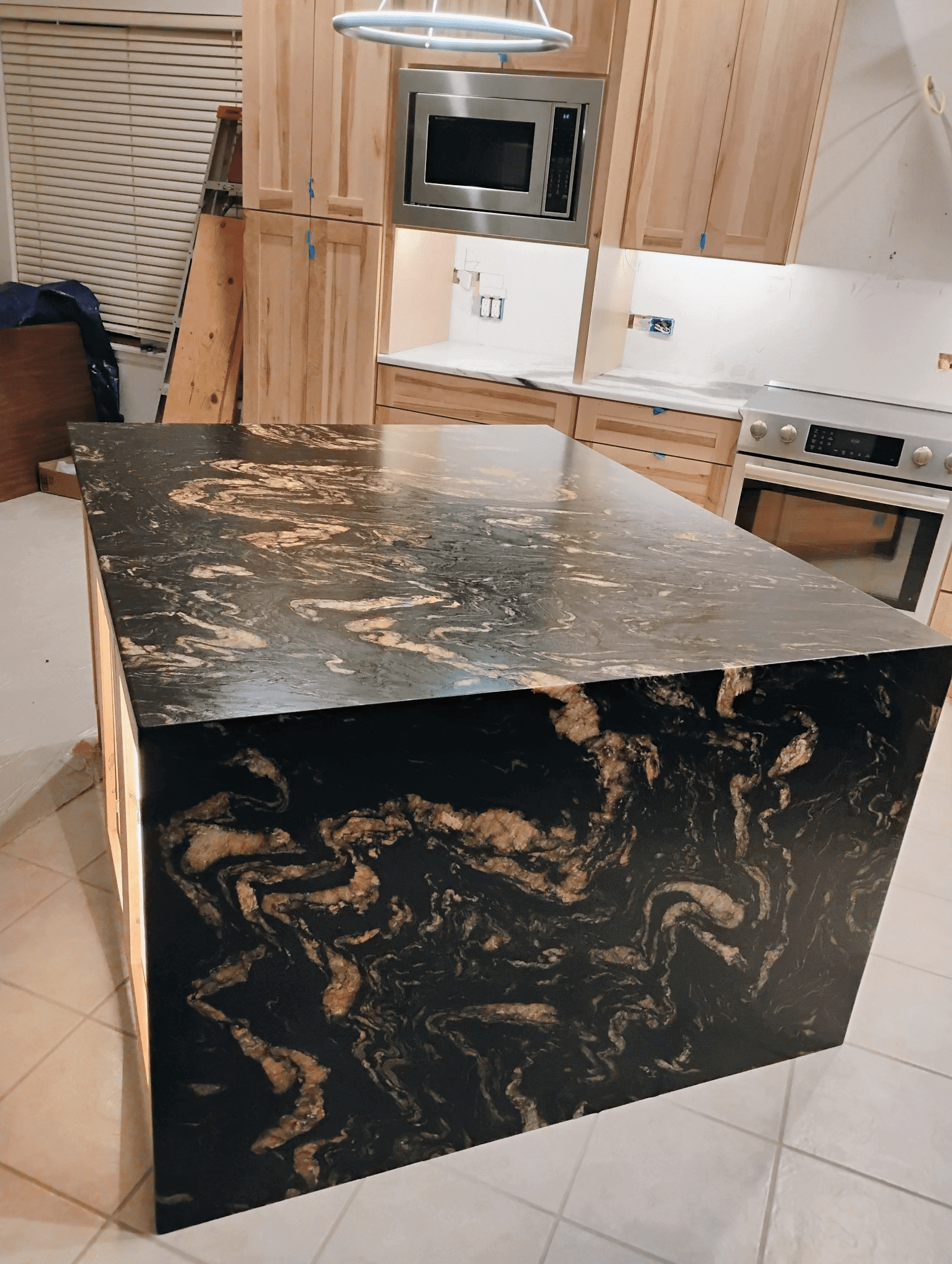 Black marble kitchen island with wood cabinets.