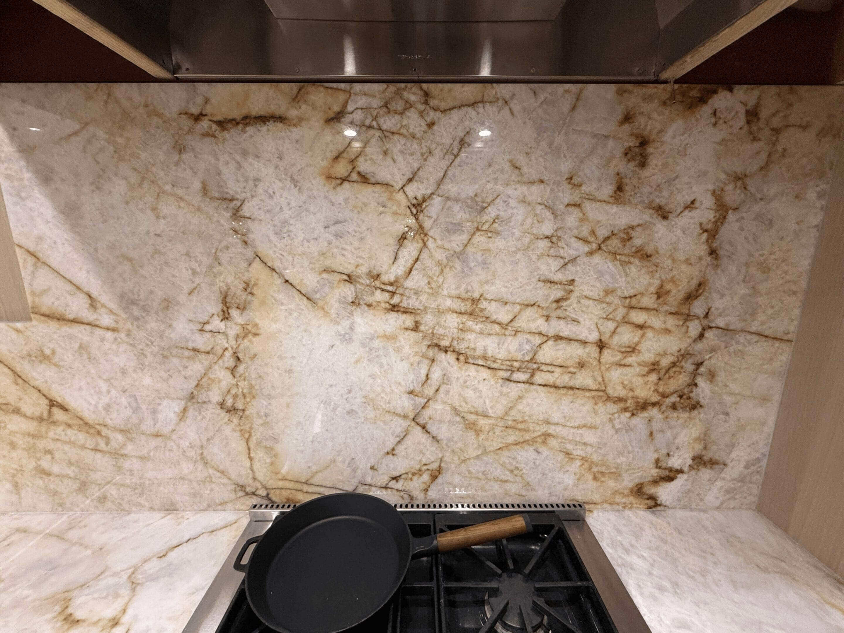 Marble backsplash with stove and pan.