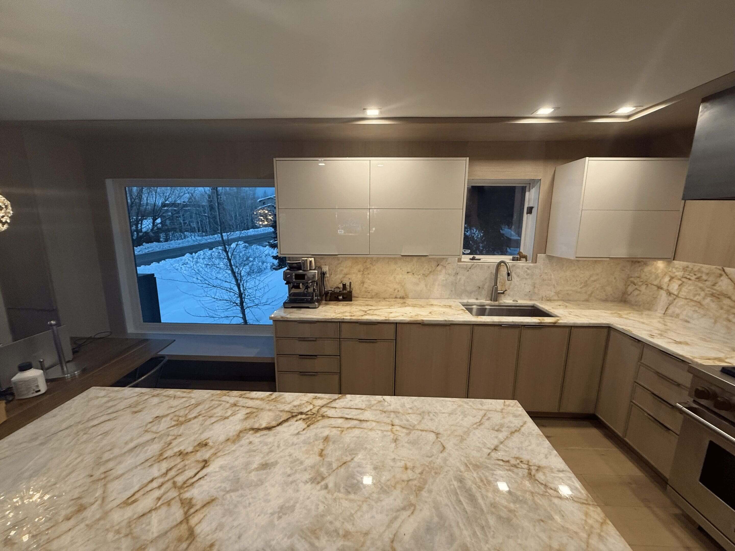 Modern kitchen with marble countertops and snow view.