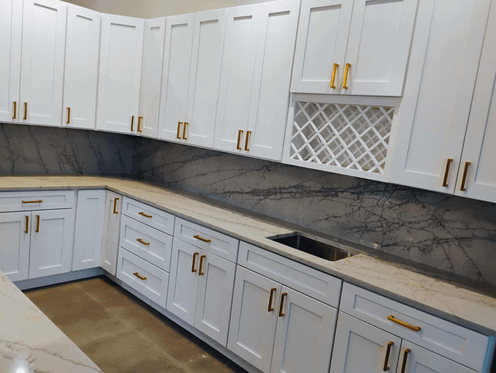 White kitchen cabinets with marble countertops.
