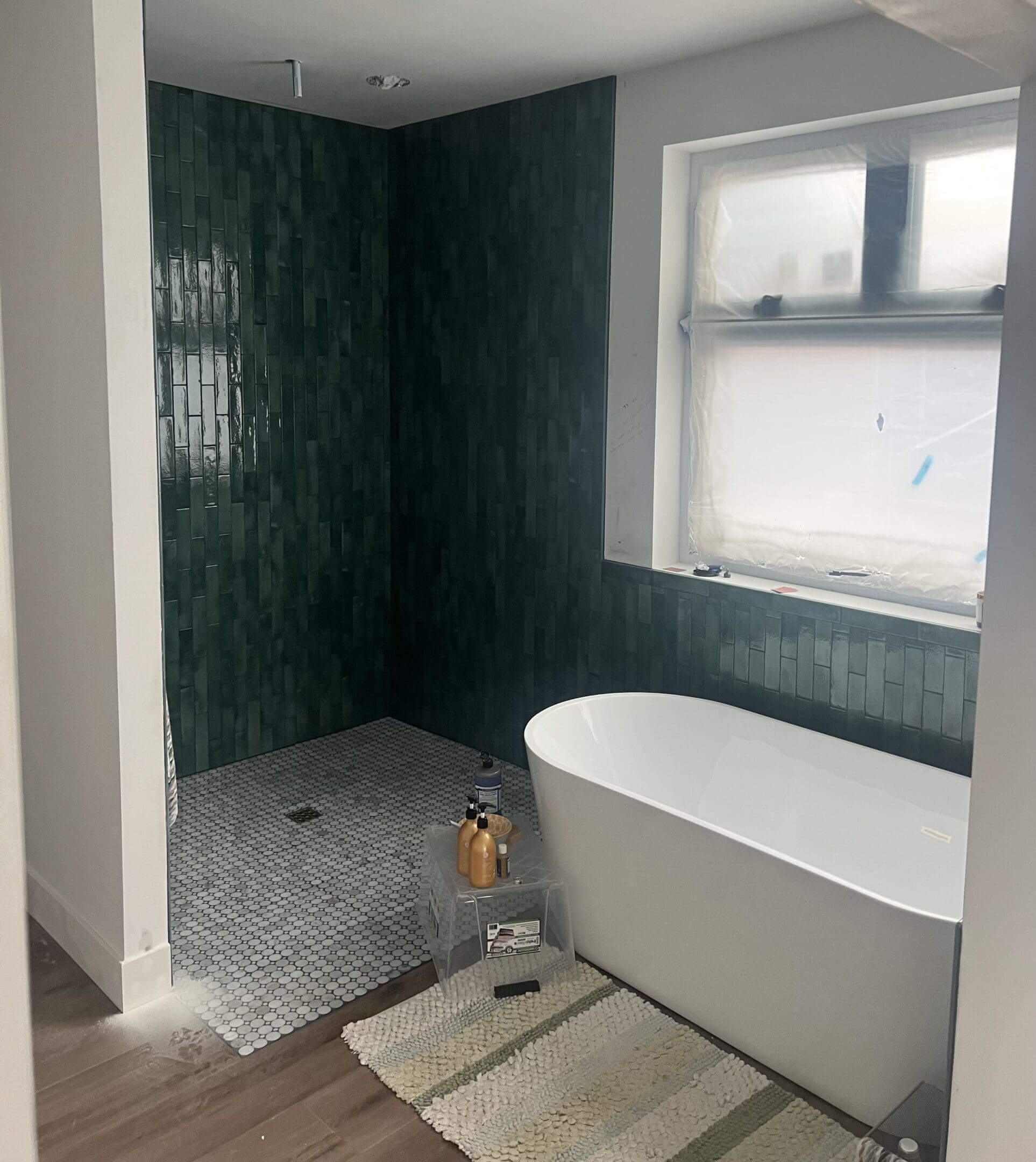 Modern bathroom with green tiled shower area.